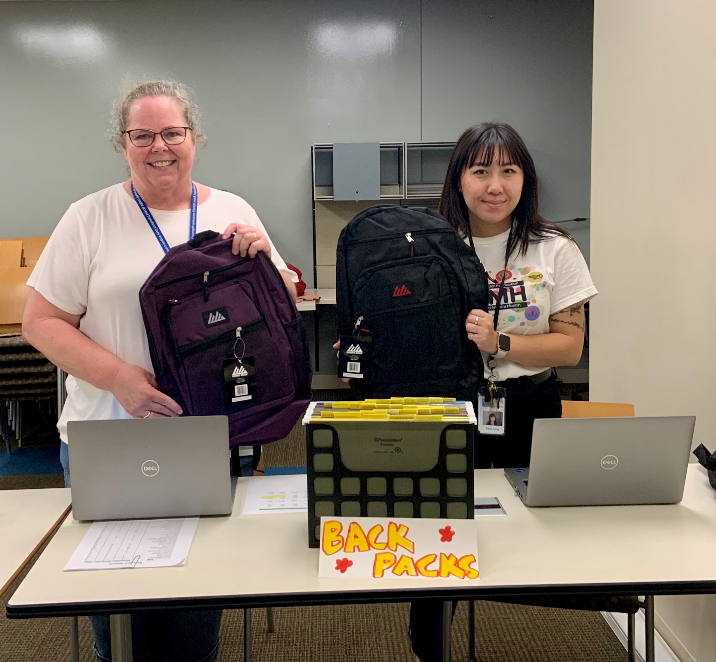 Two volunteers with backpacks at a back to school celebration