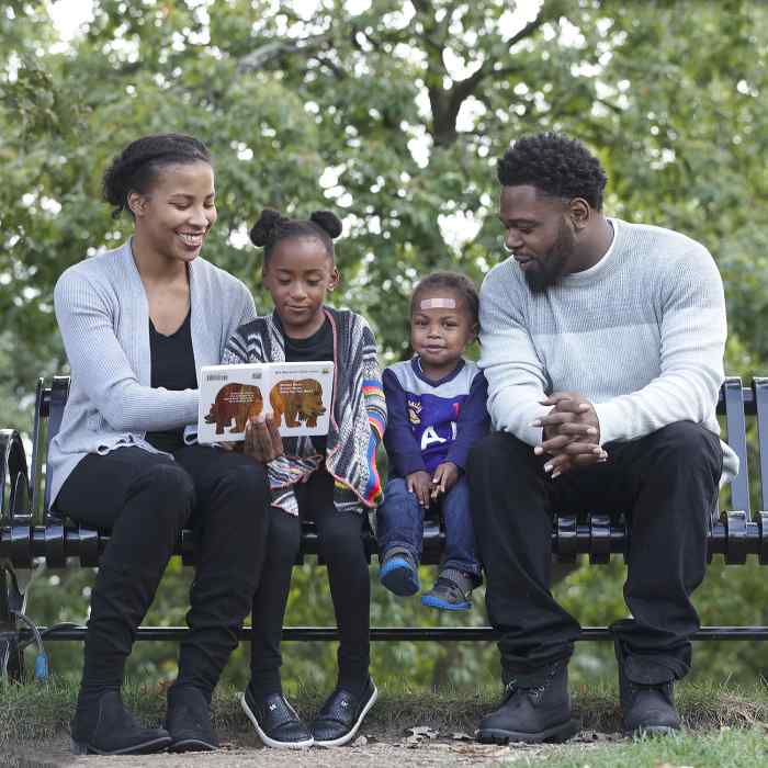 African American family sitting on park bench, african american mother and father with daughter and son, child development center family, minnesota community childcare, preschool family in saint paul minnesota