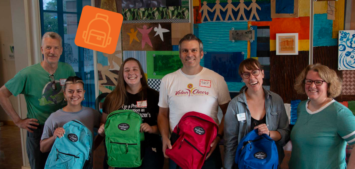 A row of six staff and volunteers who packed backpacks for students served by Wilder