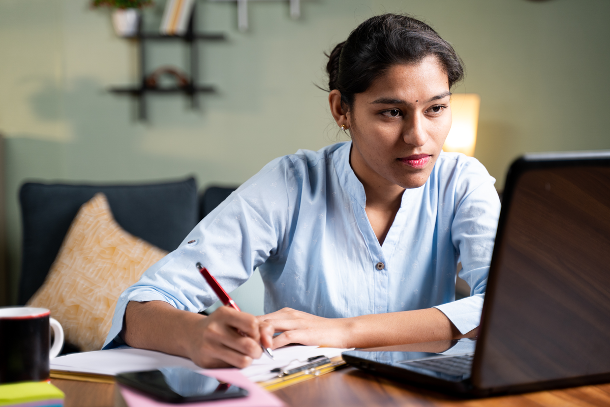 A woman takes notes while filling out an online application.