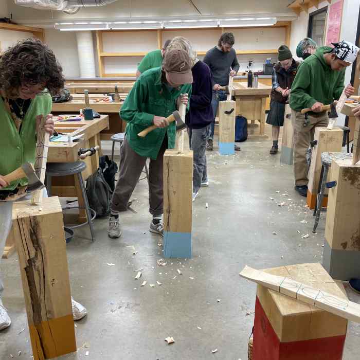 A group of students carve spoons out of wood.