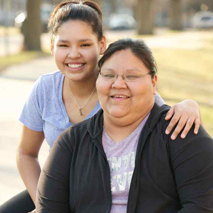 Teenage girl sitting with her arm around an older woman