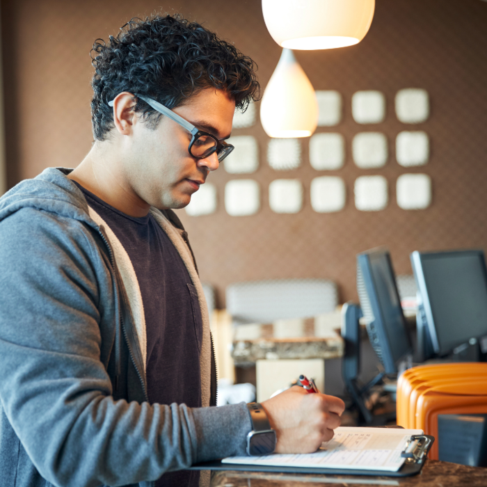 A person fills stands at an office counter filling out a form.