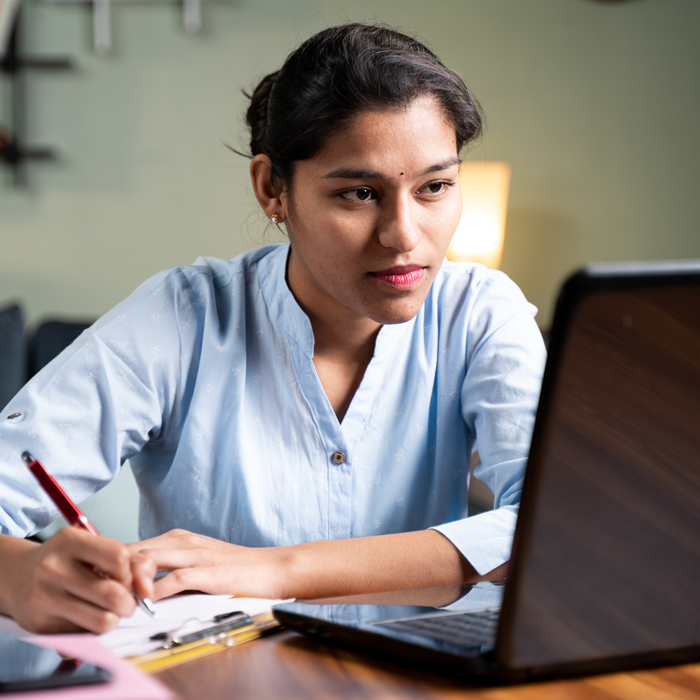 A woman takes notes while filling out an online application.