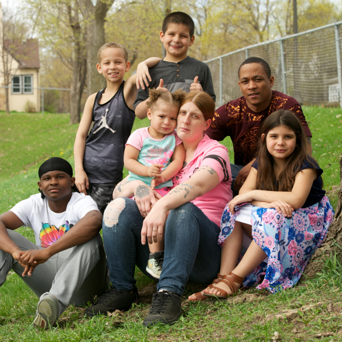 Family with children smiling with house in the background