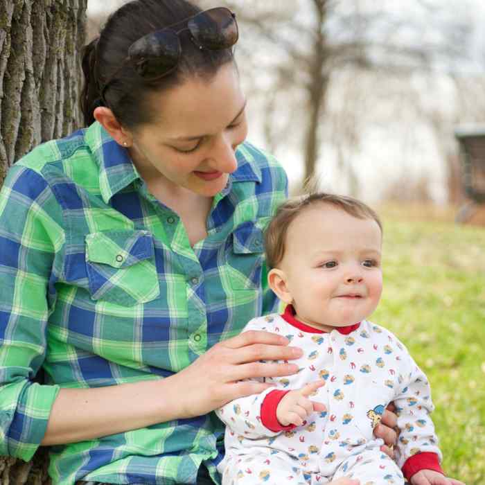 Young mother holding her baby sitting under a tree