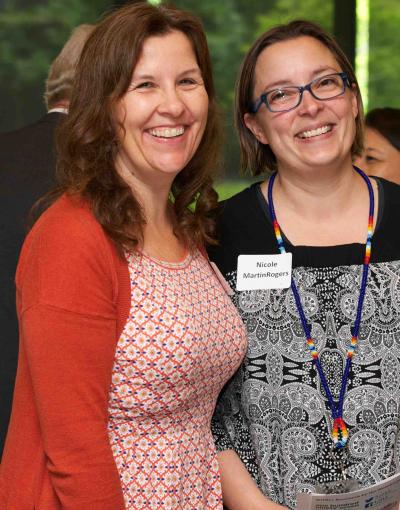 Two smiling women standing next to each other at a conference