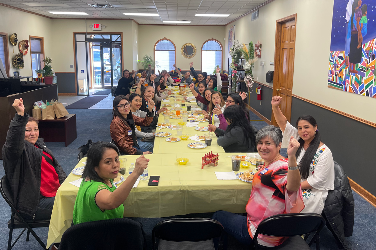 A group of women gathered along a long table enjoying a meal together.  