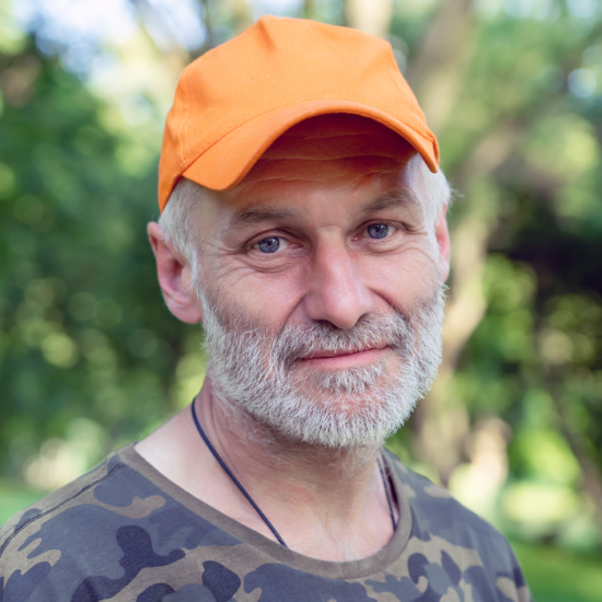 A bearded man in a cap and camouflage t-shirt. 