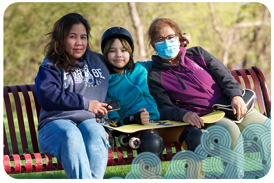 Three women sitting on park bench on a spring day, youngest in the middle wearing a helmet, kneepads and holding a skateboard