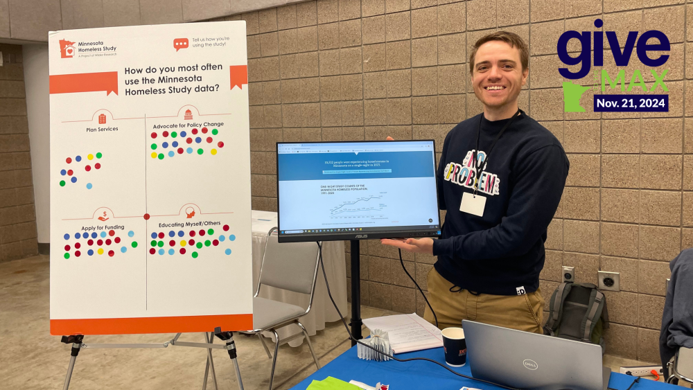 A person standing at an exhibit table presents study data. 