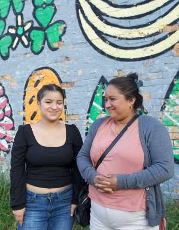 two women in front of a mural