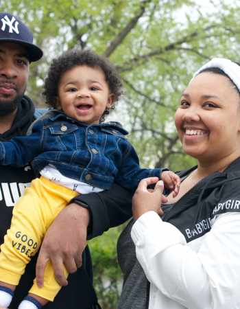 Black family of mother, father and child smiling and enjoying the park.